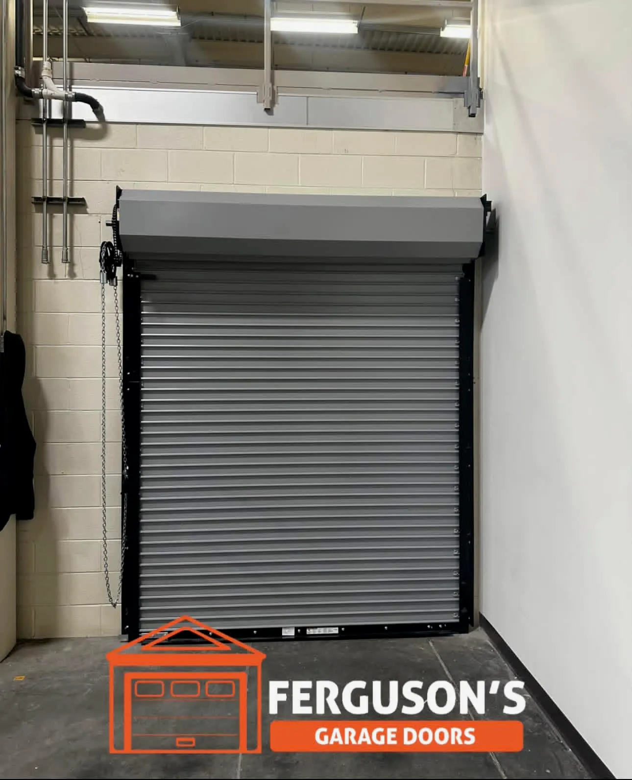 Commercial gray rolling slat door with chain hoist in warehouse interior