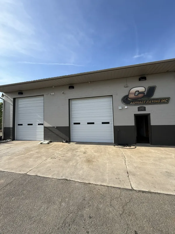 Two white ribbed commercial steel garage doors on industrial building