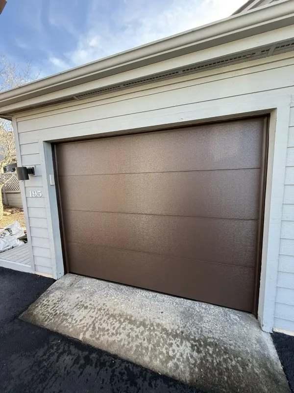 Brown flush panel steel garage door on residential home
